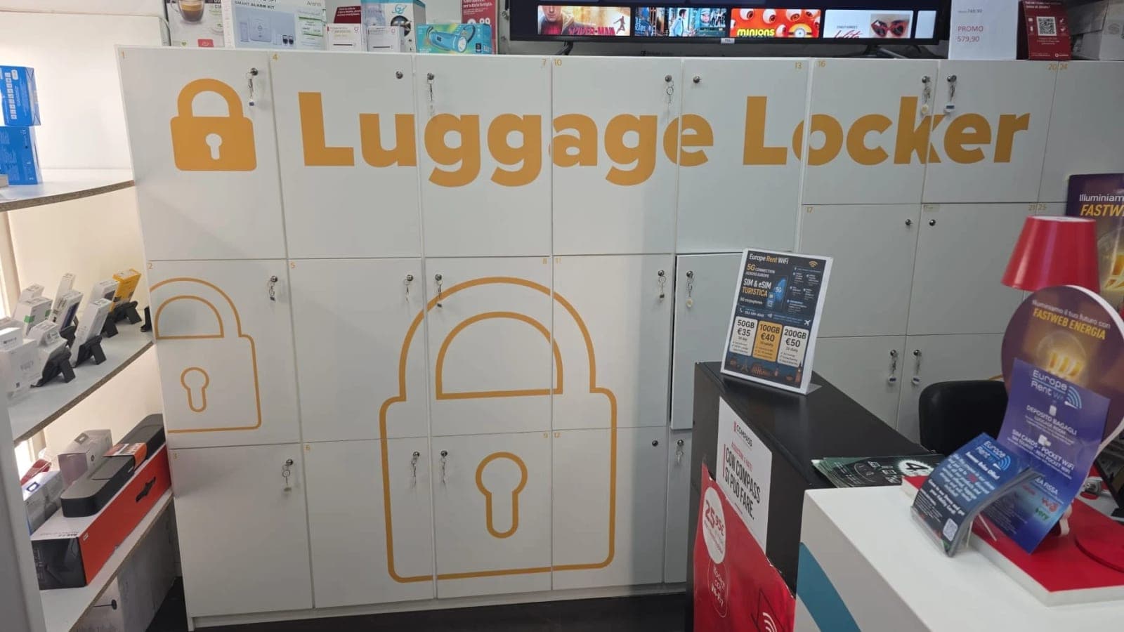 Armadietti bianchi numerati con le chiavi nel negozio di Largo Alinari, sotto un’insegna arancione «Luggage Locker»